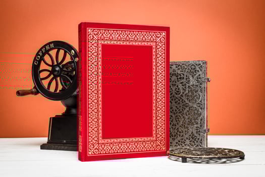 Crafting memories with a red notebook, vintage press, and intricate metal decor on a warm background photo