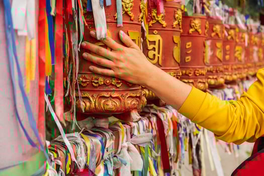 Person pilgrim female hand touching turning spinning Buddhist prayer wheel at Buddhist monastery. Prayer wheels in Buddhist stupa temple. Buddhism religion concept photo