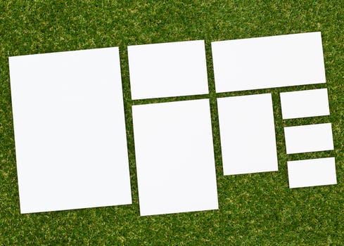 Various blank sheets of paper arranged on grass during daylight hours for creative use photo
