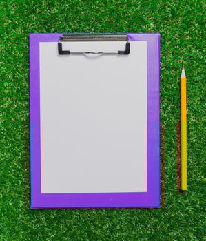 Blank clipboard and pencil on bright green grass in an outdoor setting for creative activities photo