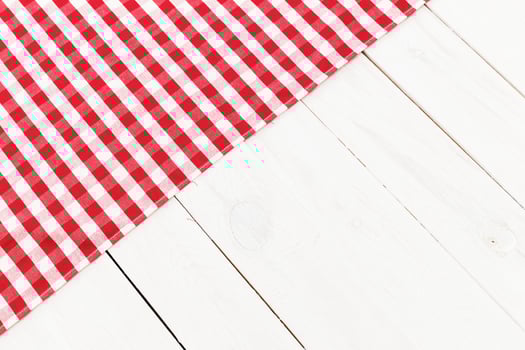 Table setting on a white wooden surface with a red and white checkered cloth for a casual dining experience photo