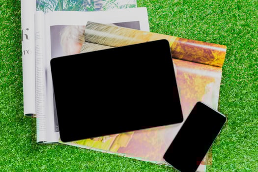 Stylish workspace with tablet and smartphone on magazines in a green grass setting photo