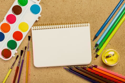 Art supplies arranged on a textured surface with a blank sketchbook ready for creativity photo