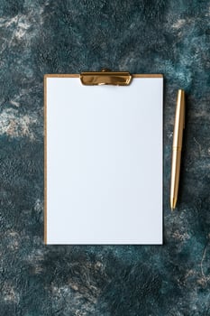 Clipboard with blank paper and gold pen on a textured background photo