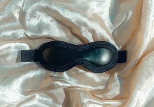Black sleep mask on a silky golden fabric photo