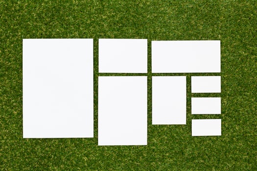 Multiple blank sheets arranged on grass for creative projects, design ideas, or presentations in a natural setting photo