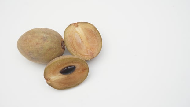 Halves and Whole Sapodilla Fruit on White Background photo