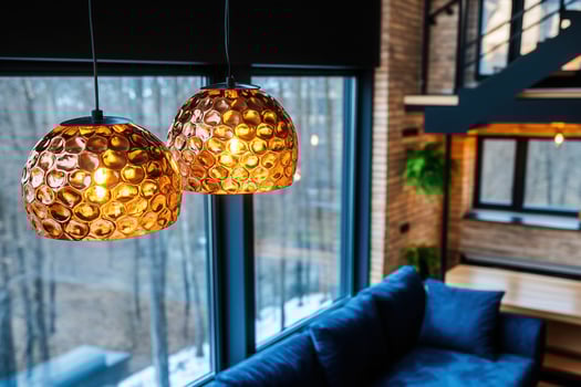 Modern loft-style living space featuring copper chandeliers and dark industrial decor with large windows for natural light photo