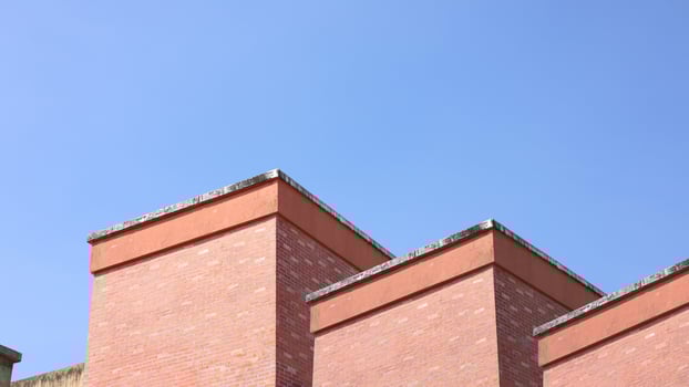 Red brick apartment building with sky, Shapes and simplicity of architecture, Fragment of roof of modern private dwelling house against of sky, Blue sky and Sunlight in background with copy space. photo