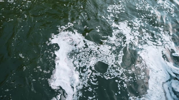 A captivating and mesmerizing view of a shimmering water surface showcasing swirling currents and frothy foam photo