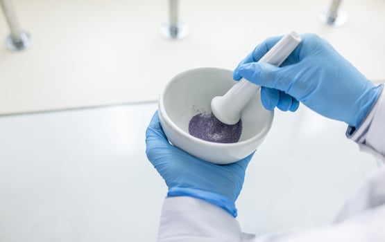 A person in a lab coat is holding a bowl with purple liquid photo