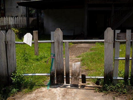 A horizontal shot of rundown white picket fence reinforced with steel and wire showing wide holes photo