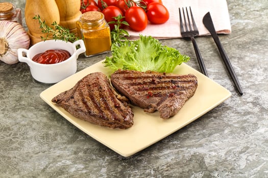 A plate of steak with vegetables and a bottle of ketchup photo