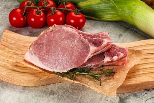 Raw pork on a cutting board with vegetables photo