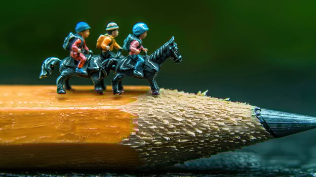 Miniature figures of riders on a pencil, showcasing creativity in a vibrant outdoor setting photo