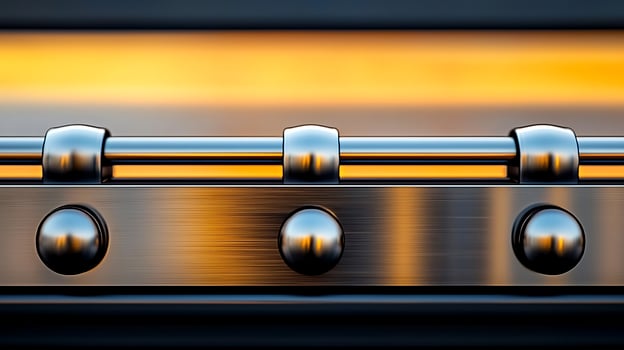 Close-up of a metallic hinge reflecting warm light against a blurred background, showcasing detail photo