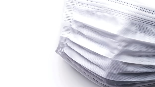 Close-up of a white surgical mask highlighting its texture and folds against a bright background photo
