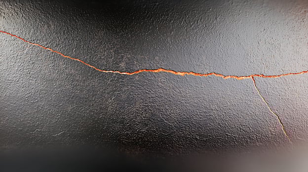 Close-up view of a cracked black surface with orange highlights, showcasing texture and depth photo