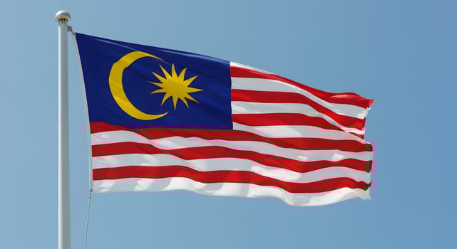 Majestic Malaysian Flag Fluttering in the Breeze Against a Clear Blue Sky photo