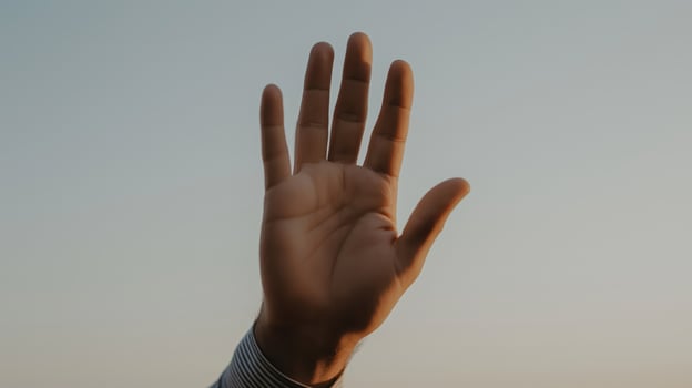Hand raised against a sunset background showcasing human expression and connection. photo