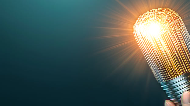 Hand holding a glowing light bulb with radiant beams against a dark blue background photo