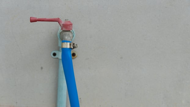 Hose clamp for water sprayer. Holds the hose from coming off the faucet. Water pipes installed on the cement wall. photo