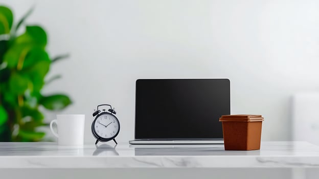 Modern workspace with a laptop, clock, coffee cup, and plant, creating a serene atmosphere photo