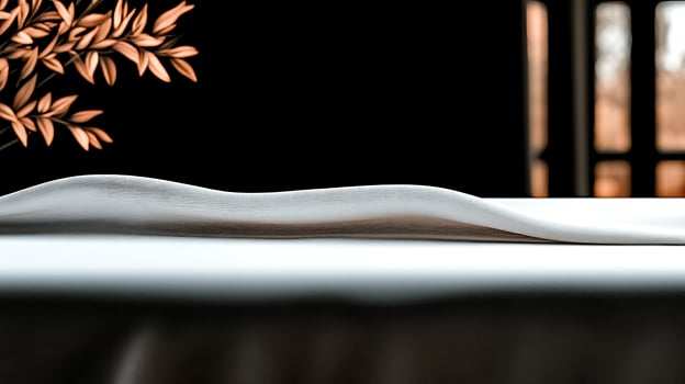 Serene table setting with a flowing white cloth and natural foliage, creating a peaceful ambiance photo