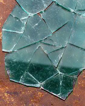 Broken glass shards on a rusty metal surface photo