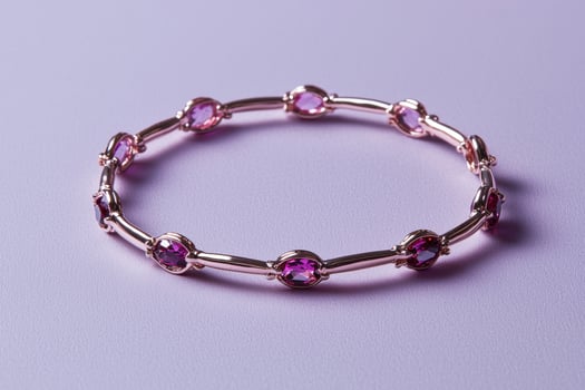 Elegant rose gold bracelet with pink gemstones on a light purple background photo
