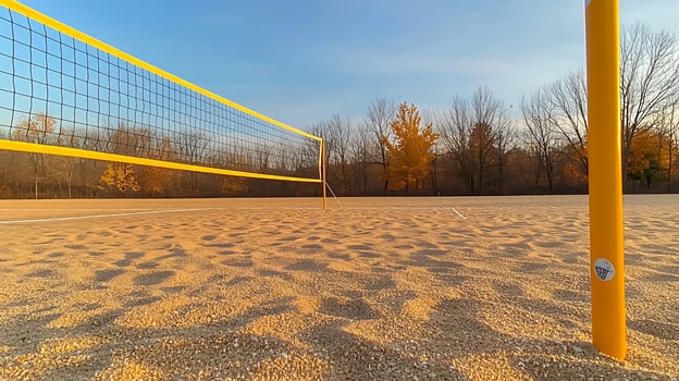 Sunset over an empty beach volleyball court with a net and autumn trees in the background photo