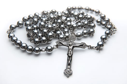 Silver rosary beads with crucifix resting on white background photo