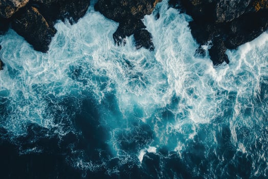 Powerful ocean waves crashing against rocky cliff, a breathtaking aerial view of nature photo