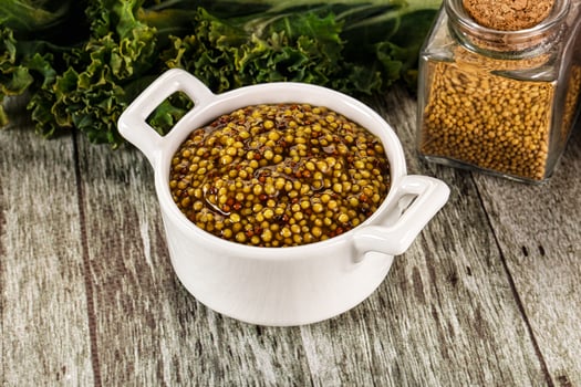 A bowl of mustard and a jar of mustard seeds photo
