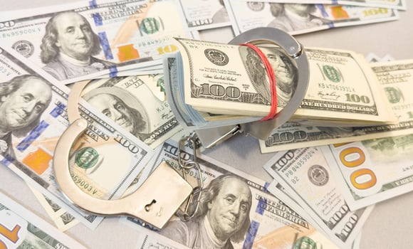Financial crime, fraud, money laundering, corruption, or law enforcement . Bundles of US dollar 100 bills in a small case, alongside a pair of handcuffs placed over the US dollar currency. photo