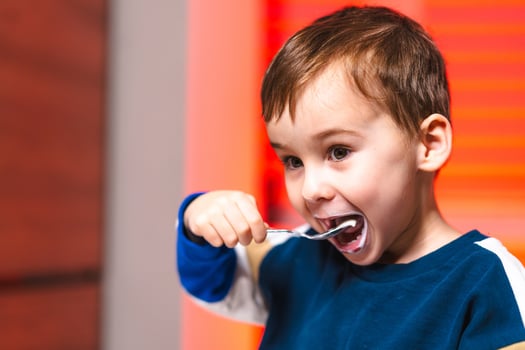 Boy savoring chocolate dessert. A cheerful young boy smiles as he takes a bite of chocolate dessert photo