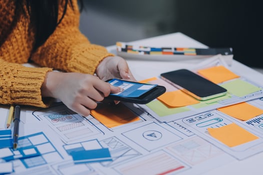 A woman using a smartphone to design a website photo
