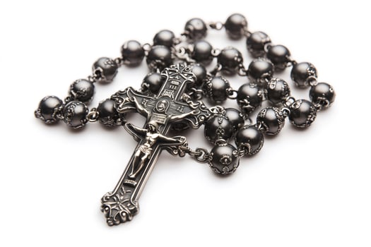 Silver rosary with detailed crucifix resting on white background photo