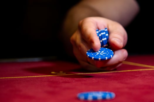 A person holding a poker chip on a red table photo