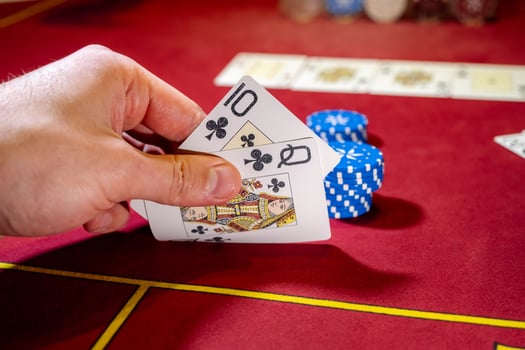A person holding a card in front of a casino table photo