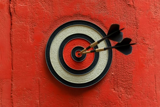 Three darts hitting bullseye on red target photo