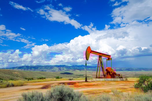Red pump jack extracting crude oil under blue sky in the desert photo