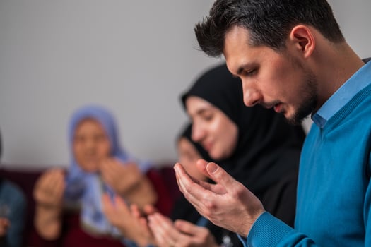 Muslim family together making iftar dua to break fasting during Ramadan at home young father praying with hands up. photo