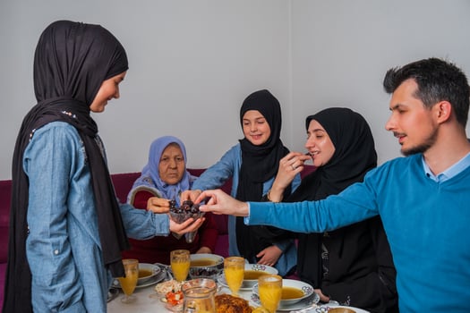Happy Muslim family having iftar dinner at home during Ramadan dining table eating dates to break fast. photo