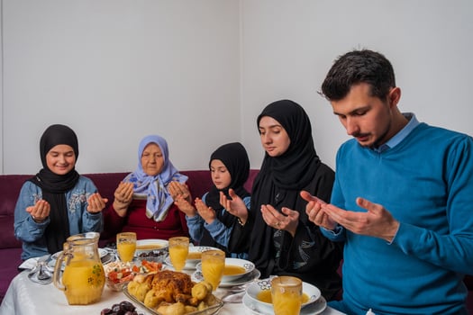 Muslim family making iftar dua to break fasting during Ramadan happy parents having dinner with their children and grandmother at dining table at home. photo