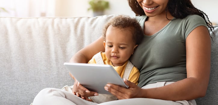 Happy Young Mother And Her Adorable Baby Son Relaxing With Digital Tablet At Home, Watching Development Videos Or Cartoons While Sitting Together On Couch In Living Room, Free Space photo