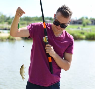 Young fisherman holds crucian carp on fishing rod against a pond photo