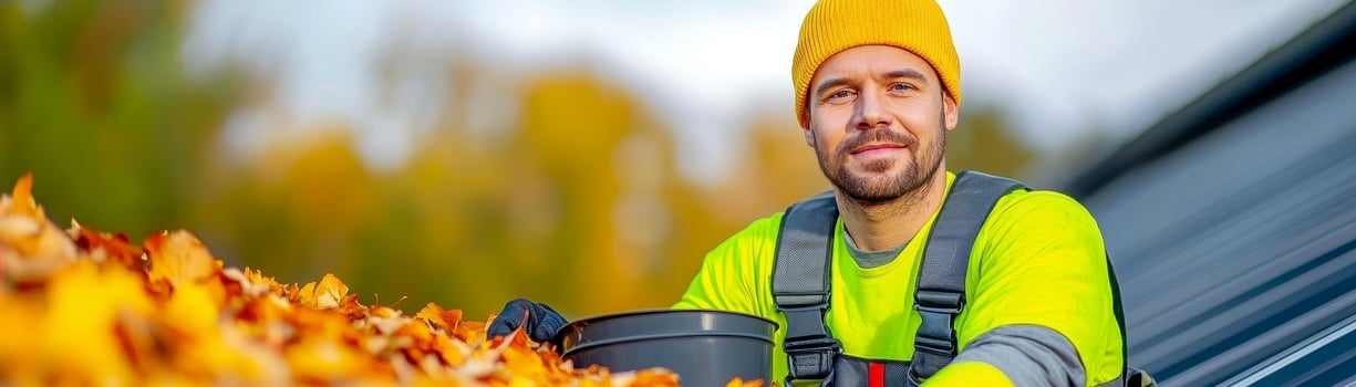 Man in Yellow Vest Collecting Autumn Leaves Outdoors photo