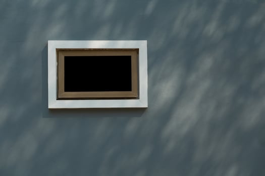 Gray wall of the house with a white small window. The wall of the house is plastered and painted gray. Lonely white window on the gray wall of the building. photo