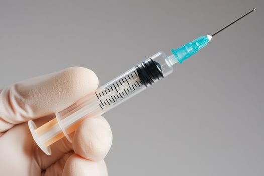 Doctor wearing latex glove holding medical syringe containing vaccine photo